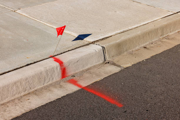 Close-up of red flagged label with spray line on curb for geodesic surveying. It represent limit availability.