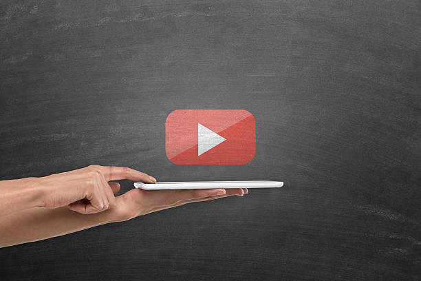 Woman holding digital tablet under you tube play icon on blackboard
