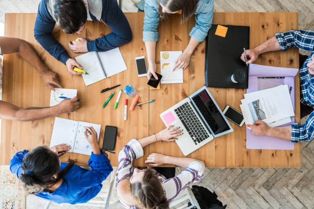 Top view of young business team working together at office. Woman pointing at a chart and explaining the analysis about business strategies.