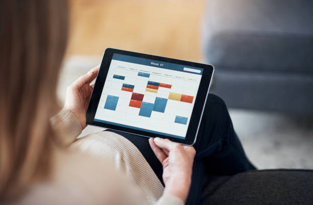 Cropped shot of an woman sitting and viewing a timetable on a tablet.