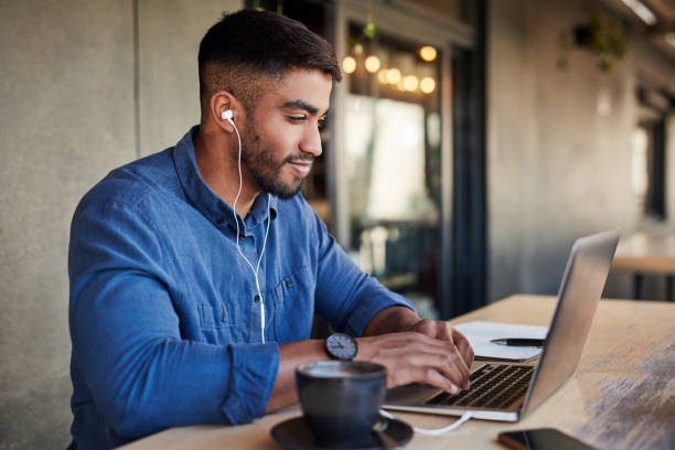 Man, earphones or laptop typing in cafe or restaurant for work. 