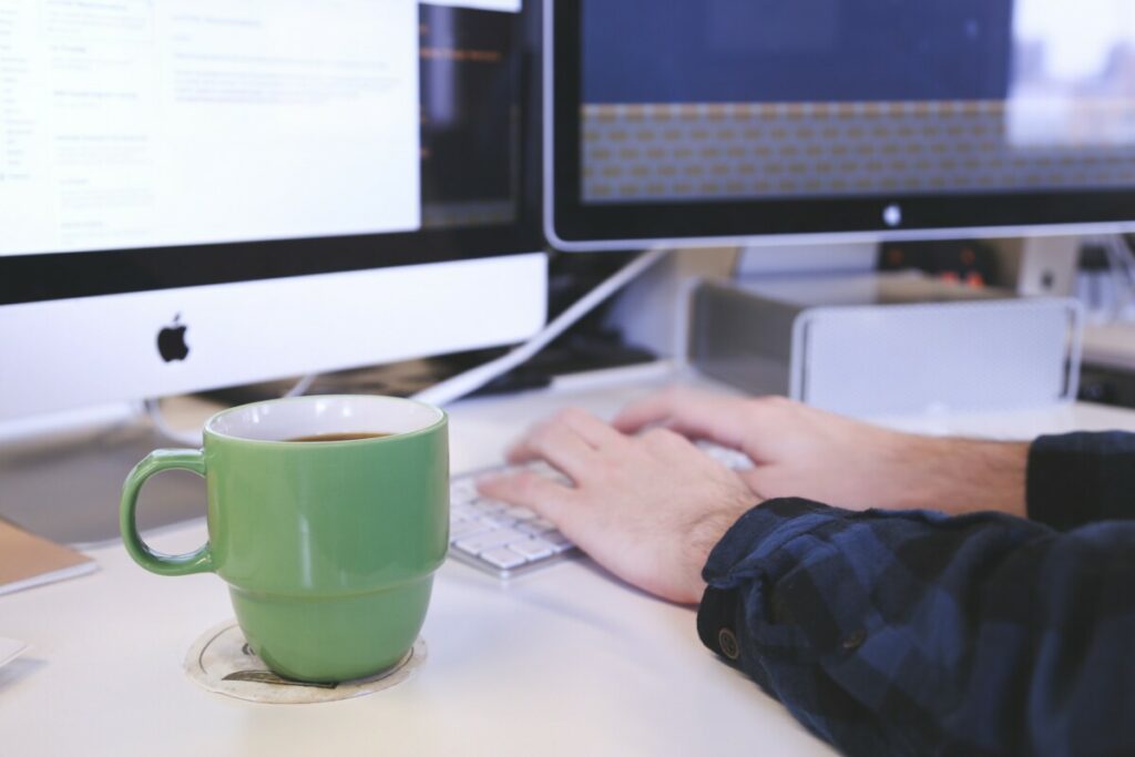 a man is typing on a computer and drinking coffee