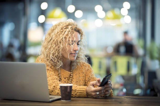 One woman using phone and laptop sitting at the cafe in airport gate waiting room. Alternative travel and job lifestyle. Business people using free wireless connection and working alternative office