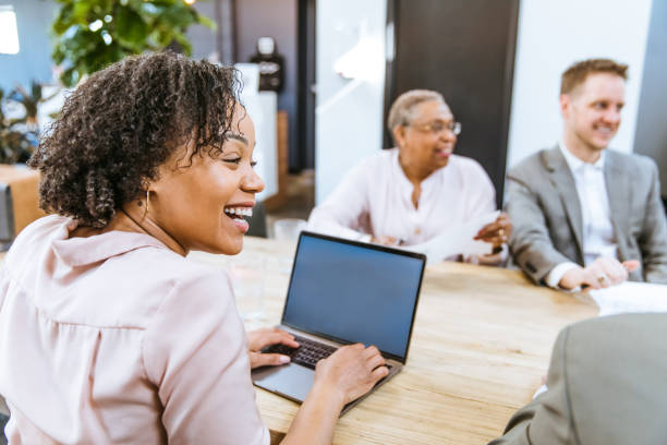 How To Choose the Best Meeting Minutes Software? biracial smiling woman typing on a laptop computer at a meeting